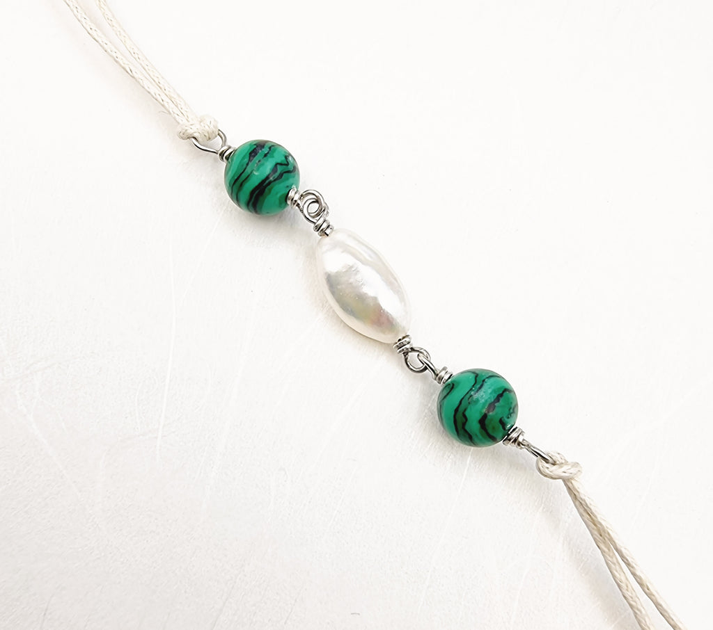 A handmade Rakhi delicately designed and crafted with synthetic Malachite and cultured white lustrous Freshwater Baroque Pearl. Truly unique and one-of-a-kind!
