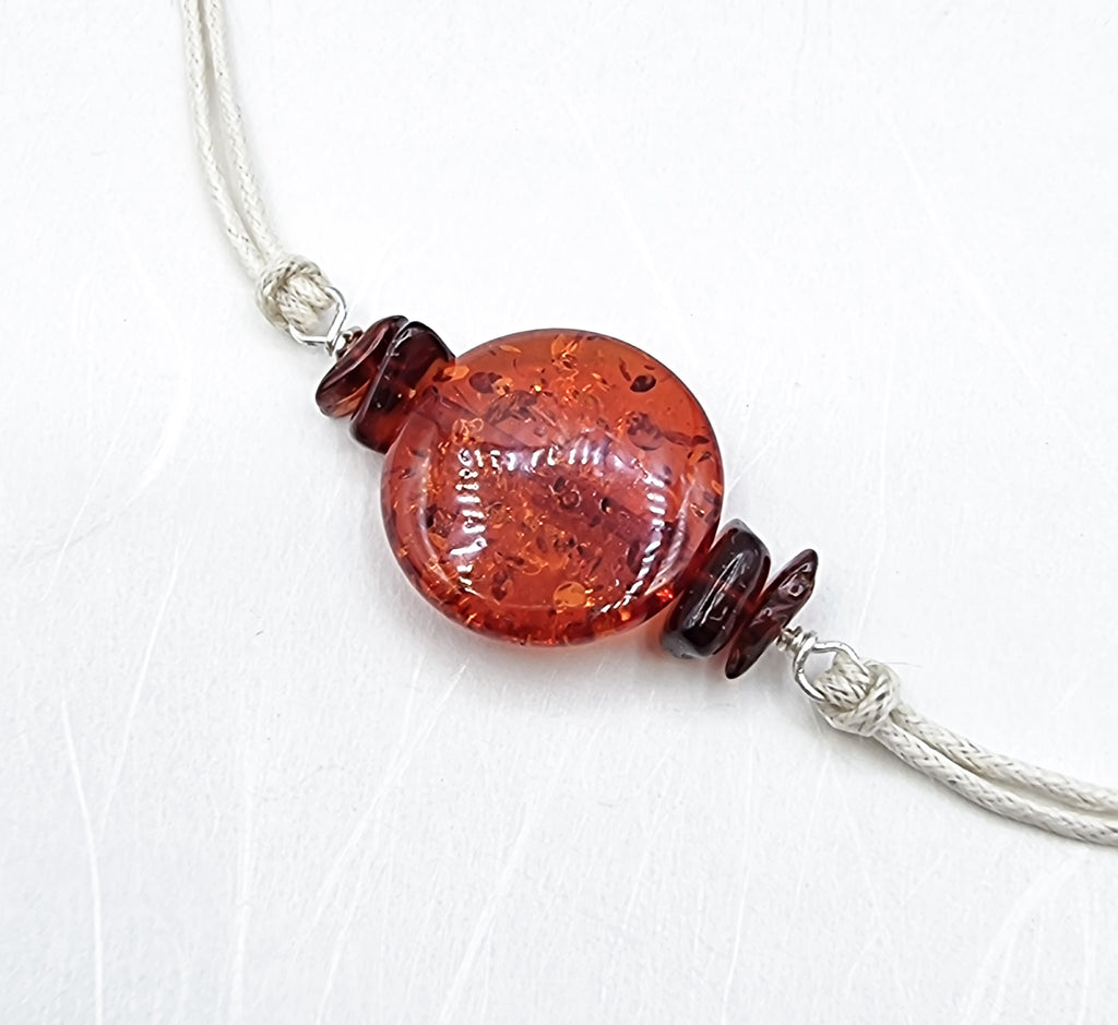 A handmade Rakhi delicately designed and crafted with acrylic orange-red amber disc accent, with tiny natural cherry red amber chips. Truly unique and one-of-a-kind!