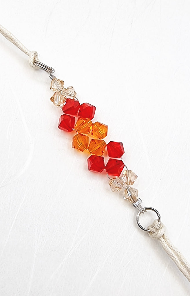 A handmade Rakhi delicately crafted with gorgeous imitation crystals in traditional red, white and orange tones, handwoven for a special touch. This elegant and sparkling design adds a touch of love and sparkle in the special sibling bond. Truly unique and one-of-a-kind!